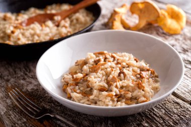 Bir kase lezzetli Cantharellus cibarius risotto rustik ahşap masa üstüne.