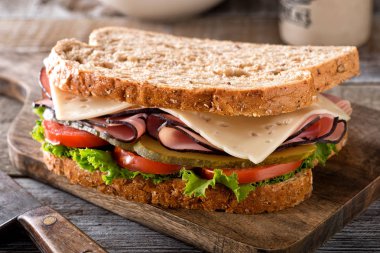 Marul, domates, dereotu turşu bir rustik ahşap tablo ile lezzetli bir jambon ve peynirli sandviç.