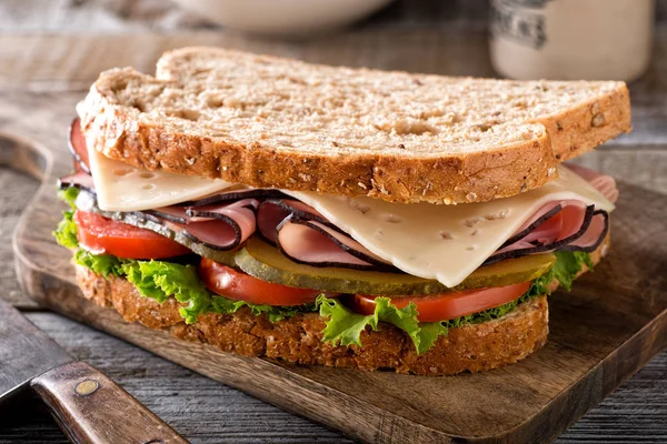 Marul, domates, dereotu turşu bir rustik ahşap tablo ile lezzetli bir jambon ve peynirli sandviç.