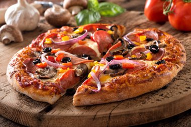 Rustik ev yapımı biberli pizza mantar, biber, kırmızı soğan ve rustik bir tahta üzerinde siyah zeytin.