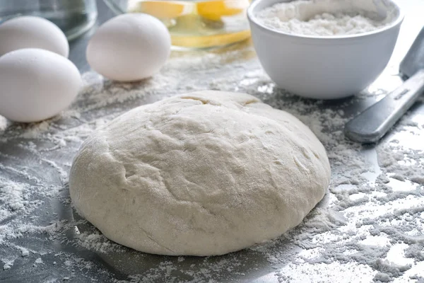 Freshly made pizza bread dough on a stainless steel counter top.