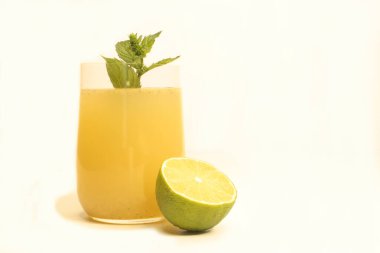 Limonatalı cam, yarım limon ve açık arkaplanda bir tutam nane şekeri.