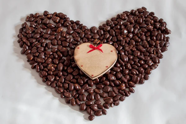 A big heart made of raisins in chocolate and a small wooden heart