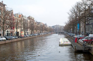 Amsterdam/Hollanda, 06 Nisan 2019: Amsterdam 'da çok sayıda kanal boyunca eski sokaklar. Nehir taşımacılığı ve bisikletler