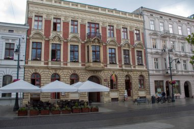 Lodz, Polonya - 09 Temmuz 2019: Yağmurlu bir yaz gününde tarihi evleri ile Polonya'nın Lodz şehrinin güzel tarihi merkezi sokak.