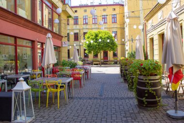 Yaz güneşli gününde şehir Lodz ağaçlarda renkli mobilyalar, çiçek açan çiçekler ve parlak şapkalar ile rahat renkli avlu.