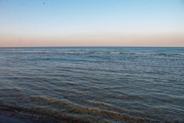 Güzel deniz manzarası - denizde gün batımı ve parlak pembe-mavi gökyüzü ve mavi sakin deniz örtüsü.