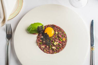 Biftek tartare ile çiğ yumurta sarısı üstüne beyaz plaka restoran servis