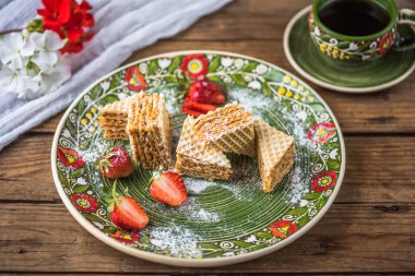 Ahşap masa üzerinde çiçek desenli tabak waffle tatlı taze çilek ile servis
