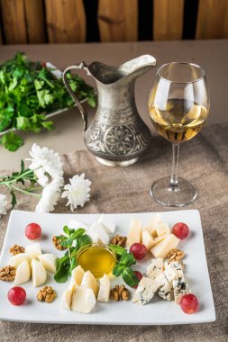 Beyaz şarap bir bardak gri masa örtüsü üzerinde peynir tabağı