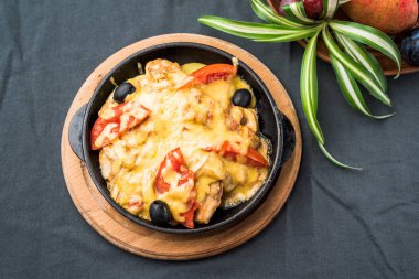 Siyah masa örtüsü üzerinde tava peynir ile pişmiş sebzeler