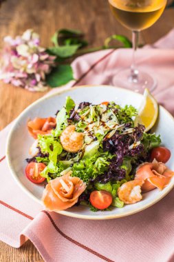 Beyaz şarap bir bardak pembe kumaş üzerinde kase taze sebze ve deniz ürünleri salatası