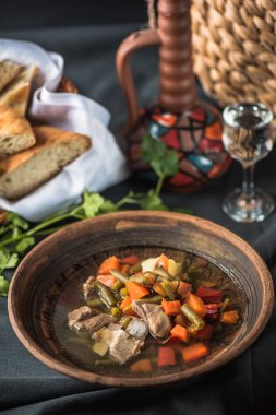 Masa ekmeği üzerinde kil kase tavuk ve sebze çorbası
