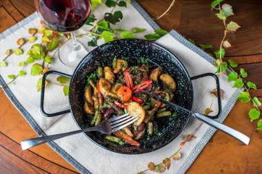 Ahşap masada kızartma tavasında kızarmış sebzeler ve mantar