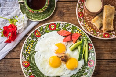 Rustik ahşap masada desenli plaka üzerinde taze sebzeler ile kızarmış yumurta