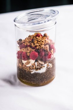 Kırmızı peçete üzerinde granola ve taze ahududu ile kavanoz tatlı