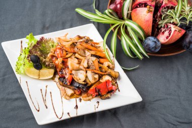 Gri masa örtüsü üzerinde plaka üzerinde pişmiş sebze ile deniz ürünleri snack