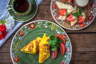 Kahvaltı - omlet karıştıran bir renk plaka ve kahve close-up krep. Köy gıda ahşap bir masa üzerine