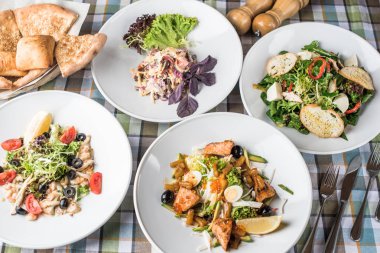 Damalı masa örtüsünde servis edilen tabaklarda farklı atıştırmalık salatalar