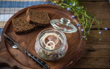 Soğan ekmek dilimleri ile ahşap tepsi üzerinde cam kavanoza salamura balık