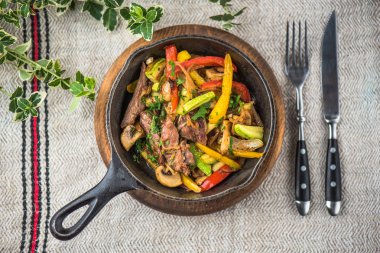 Keten kumaş üzerinde rustik tencerede et ile kavrulmuş karışık sebze