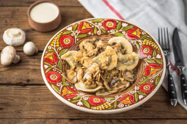 Ahşap masa üzerinde rustik çiçek desenli plaka üzerinde kızarmış yağlı mantar ile ev yapımı köfte