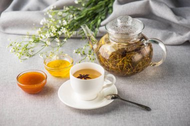 Çaydanlık ve sağlıklı bitkisel çay fincan gri masa örtüsü üzerinde servis