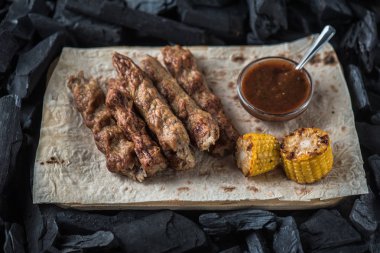 Ahşap tahta üzerinde sos ve mısır koçan ile ızgara sosis