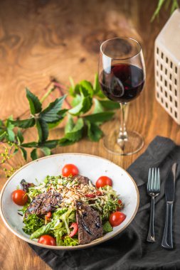 Kırmızı şarap cam ile ahşap masada kase et ile taze sebze salatası
