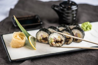 Japon Suşi roll çubuklarla gri kumaş tabakta servis