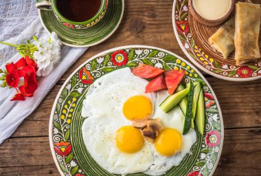 Rustik ahşap masada desenli plaka üzerinde taze sebzeler ile kızarmış yumurta