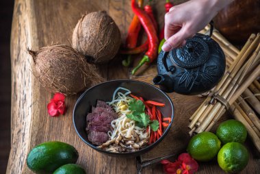 insan el Vietnamca Pho su dökerek ahşap masa üzerinde siyah kase çorba