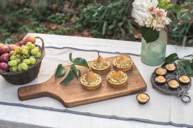 armut, üzüm, kekler ve Bahçe Festival tablo Vazoda Çiçekler ile lezzetli tartlets