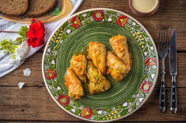 Ahşap masa üzerinde rustik çiçek desenli plaka üzerinde geleneksel lahana rulo