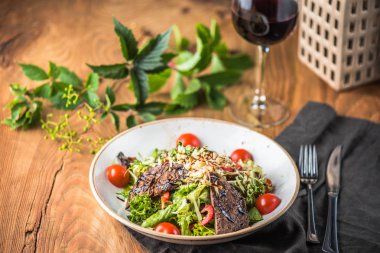 Kırmızı şarap cam ile ahşap masada kase et ile taze sebze salatası