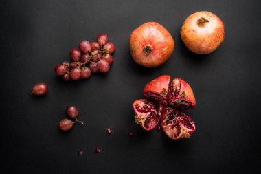 Taze sulu nar ve siyah arka plan üzerine üzüm