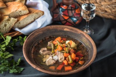 Masa ekmeği üzerinde kil kase tavuk ve sebze çorbası