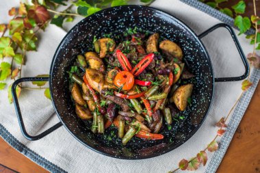 Ahşap masada kızartma tavasında kızarmış sebzeler ve mantar