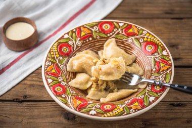 Renkli plaka ve ekşi krema rustik ahşap masa üzerinde çatal ile köfte