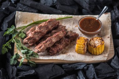 Ahşap tahta üzerinde sos ve mısır koçan ile ızgara sosis