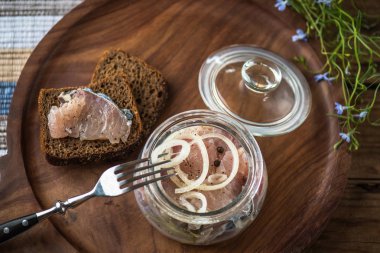 Soğan ekmek dilimleri ile ahşap tepsi üzerinde cam kavanoza salamura balık