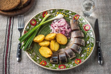 Ringa balığı kavrulmuş patates ve soğan keten masa örtüsü üzerinde çiçek desenli rustik plaka üzerinde