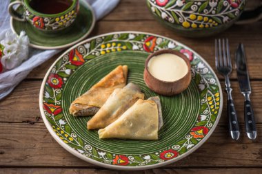 Renkli plaka ve ekşi krema yakın çekim doldurma ile krep. Köy gıda ahşap bir masa üzerine