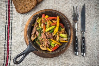 Keten kumaş üzerinde rustik tencerede et ile kavrulmuş karışık sebze
