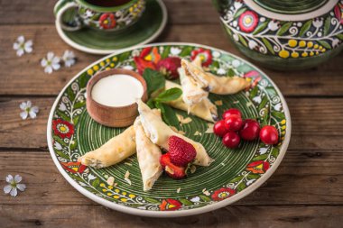 Taze çilek ve ekşi krem ile çiçek desenli plaka üzerinde tatlı haddelenmiş krep