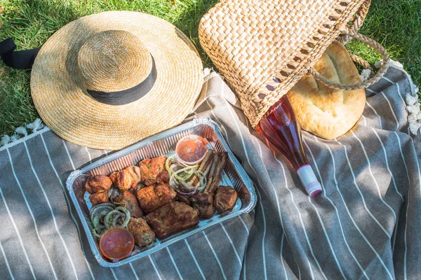 grilled meat, salad and vegetables in take away containers on blanket outdoors