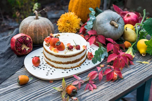 Fruits, pumpkins, cake and flowers on wooden table in garden. Seasonal still life. Autumn evening