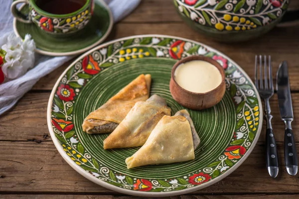 Renkli plaka ve ekşi krema yakın çekim doldurma ile krep. Köy gıda ahşap bir masa üzerine