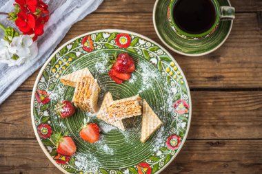 Ahşap masa üzerinde çiçek desenli tabak waffle tatlı taze çilek ile servis