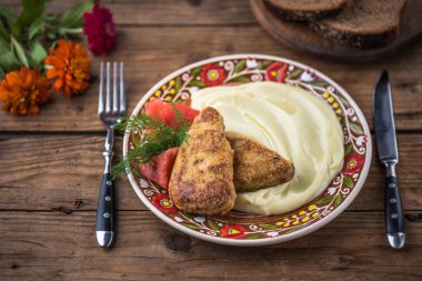 Ev yapımı kızarmış tavuk göğsü ve ahşap masa üzerinde rustik renkli plaka üzerinde patates püresi